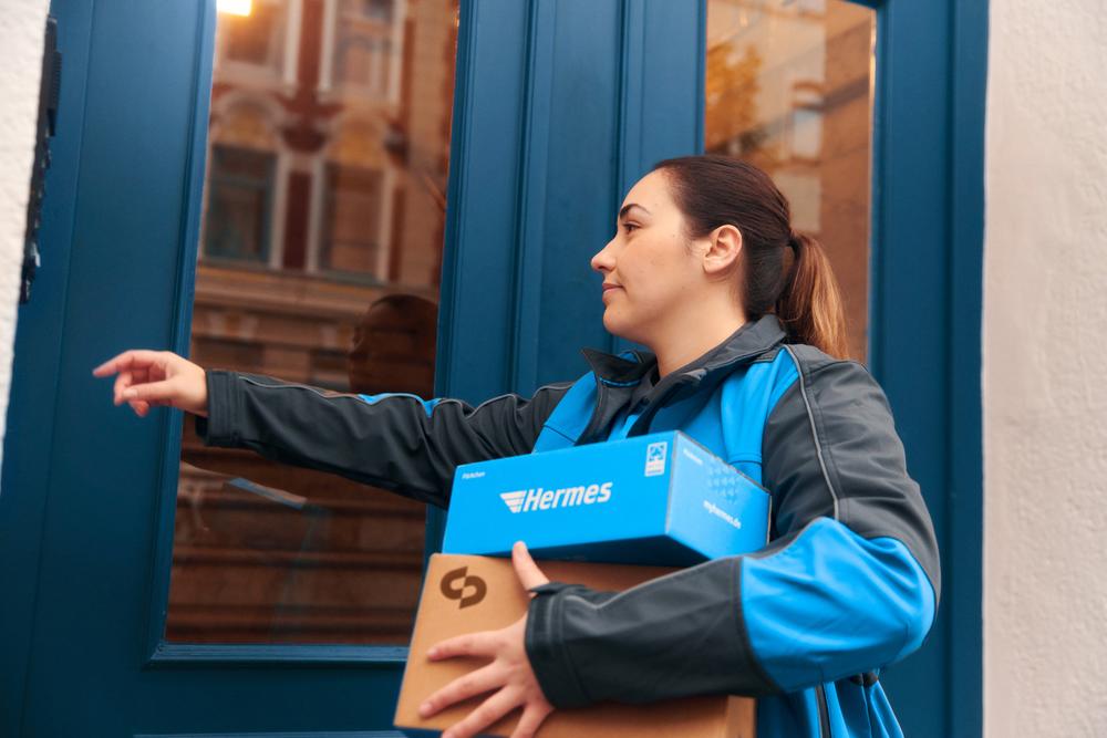 Hermes-Lieferant klingelt an der Tür zur Lieferung eines Pakets